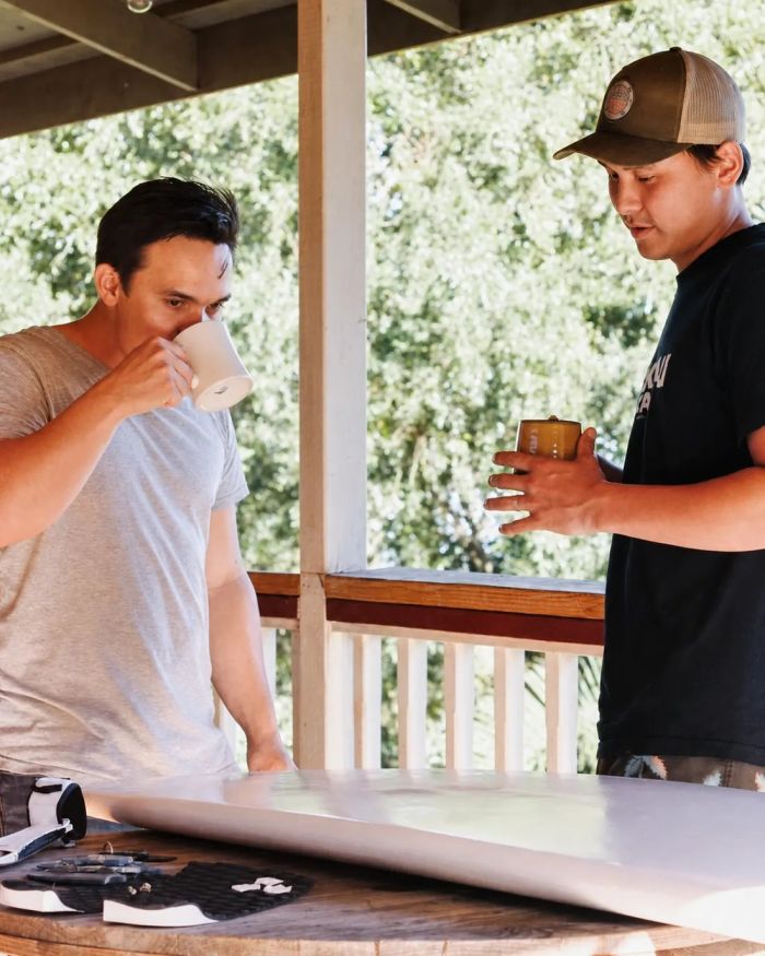 Two young men tasting coffee on the farm lanai